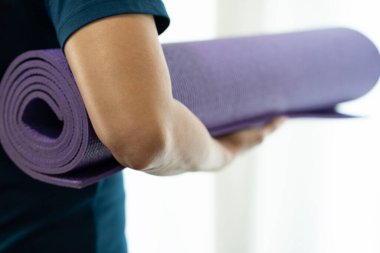 Spor ve sağlıklı bir konsept için egzersiz sınıfında yoga minderi tutan genç bir kadın.