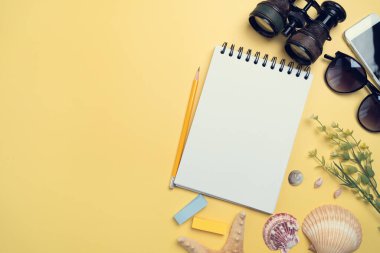 Flat lay concept of travel accessories vacation trip and long summer weekend planning on yellow table with blank space for text background.