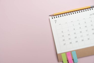 Pembe masa arkaplanındaki takvim ve kalemi kapat, iş toplantısı ya da seyahat planlama konseptini planla