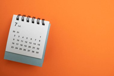 Takvimin turuncu masa arka planında kapatılması, iş toplantısı ya da seyahat planlama konsepti