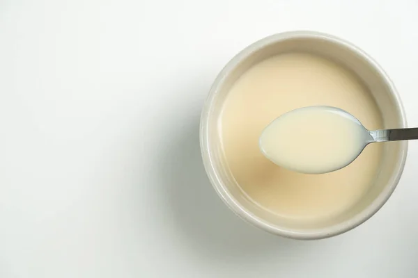 白を基調としたスプーン付き練乳のトップビュー 食材コンセプト — ストック写真