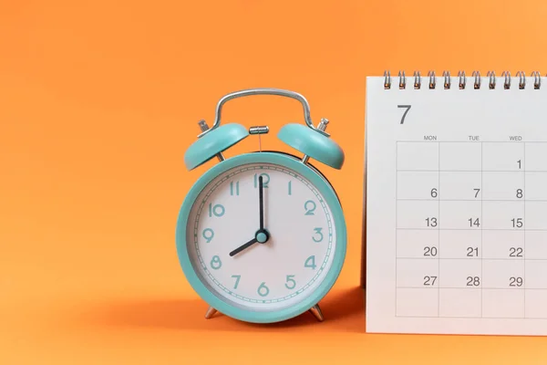 关闭橙色桌子背景上的日历和闹钟 规划商务会议或旅行规划概念 — 图库照片