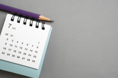 Gri masa arkaplanındaki takvimin kapatılması, iş toplantısı veya seyahat planlama konsepti için planlama