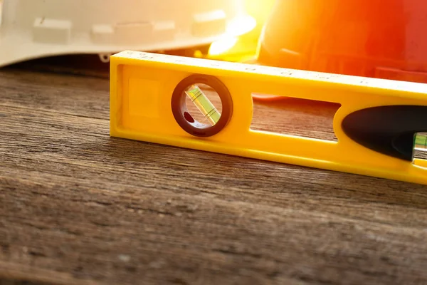 Stock image Yellow building water level gauge and helmet on the old wood table, engineering work tool concept