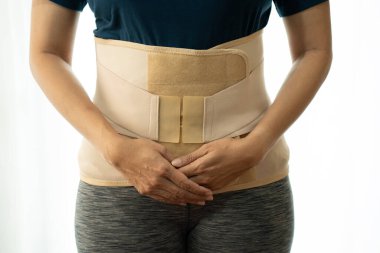 Sırtını korumak için sırt desteği takan genç Asyalı kadın, ilaç ve sağlıklı konsept.