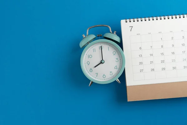 在蓝色桌子背景 商务会议规划或旅行规划概念上关闭日历和闹钟 — 图库照片