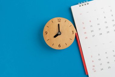 Takvimi ve saati mavi masa arkaplanına kapat, iş toplantısı ya da seyahat planlama konseptini planla