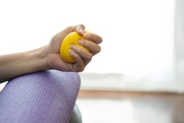 Yoga minderinde stres topu sıkan bir kadının elleri..