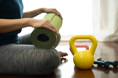 Spor ve sağlıklı bir konsept için spor sınıfında yoga minderi ve dambıl tutan genç bir kadın.