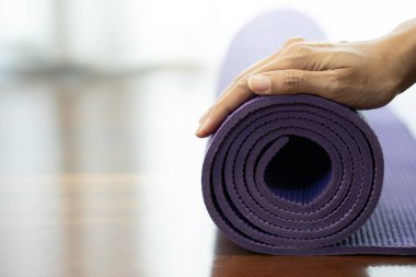 Spor ve sağlıklı bir konsept için egzersiz sınıfında yoga minderi tutan genç bir kadın.