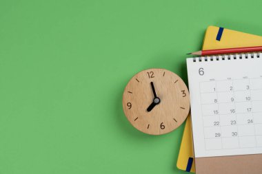 Takvim ve saati yeşil masa arka planında kapat, iş toplantısı veya seyahat planlama konsepti için planlama