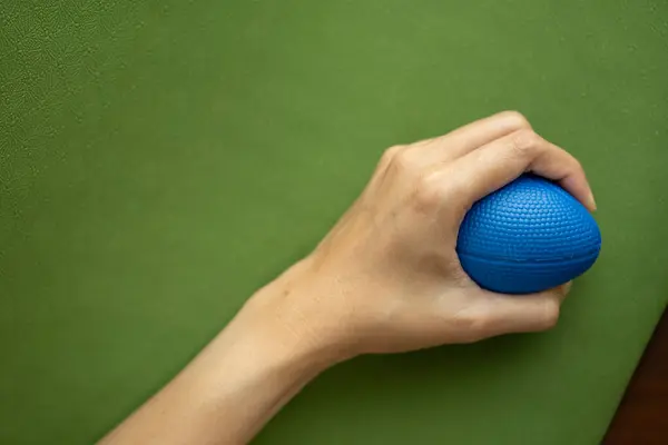 Hands of a woman squeezing a stress ball on the yoga mat, work out concpet