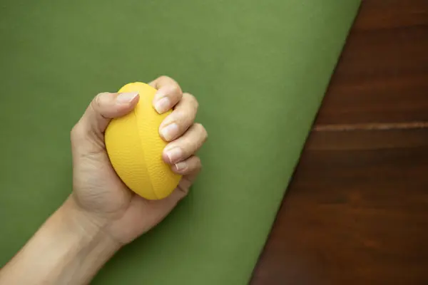 Hands of a woman squeezing a stress ball on the yoga mat, work out concpet