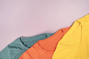 Pembe masa arkası, seyahat ve yaşam tarzı konseptine sarılmış renkli t-shirt giysilerini kapat