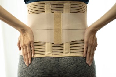 young woman wearing back support for protect her back, medicine and healthy concept