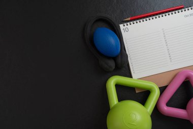 Siyah arka plan, spor ve sağlıklı konsepte sahip takvim ve dambıl çalışma zamanı