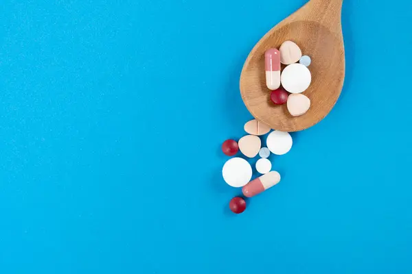 Mavi Masa Arka Planında Bir Kaşıkta Bir Sürü Renkli Ilaç Stok Fotoğraf