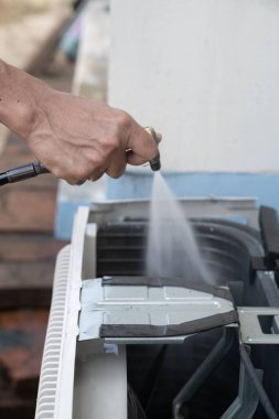 Mühendis ya da tamirci yüksek basınçlı su püskürtüsüyle havalandırma ünitesini tamir edip temizliyor.