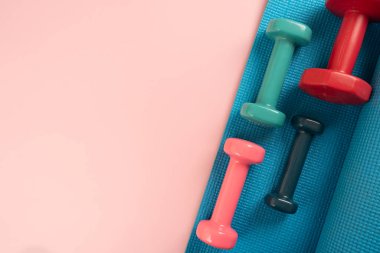Halterler ve mavi yoga minderi pembe masa arkasında, fitness sağlıklı ve spor konsepti