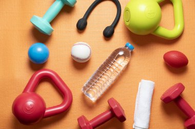 Turuncu yoga minderi arka planında spor malzemesi egzersizi zamanı. Sağlıklı ve egzersiz konsepti.
