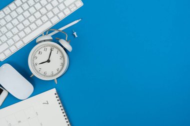 Ofiste mavi renkli masa arkaplanı üzerinde kırtasiye, takvim, alarm saati olan mühendis veya mimar masası, proje fikirleri kavramı