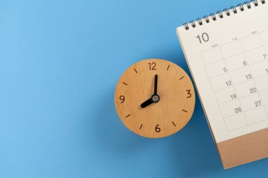 Takvimi ve saati mavi masa arkaplanına kapat, iş toplantısı ya da seyahat planlama konseptini planla