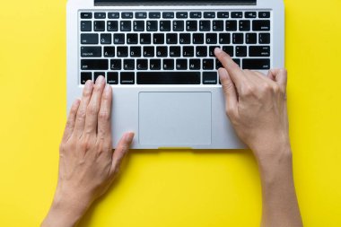 Kadın laptopta çalışırken yaratıcı ofiste ya da kafeteryada sarı masa arkasında oturuyor, iş konsepti.