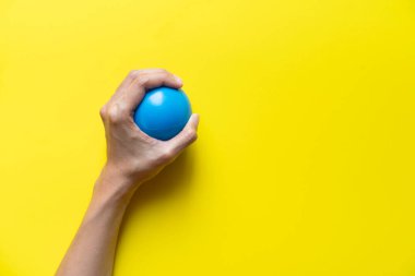 sarı arka plan üzerinde stres topu tutan kadın