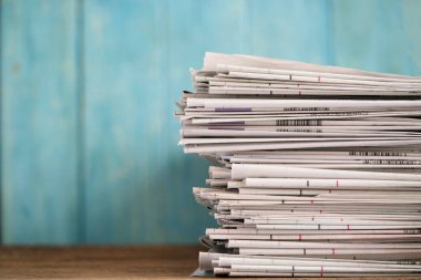 Gazeteleri kapatın katlanmış ve yeşil arka planlı masanın üzerine istiflenmiş..