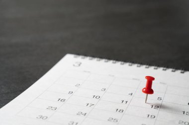 Siyah masa arkaplanındaki takvime kırmızı raptiyeyi iliştir, iş toplantısı ya da seyahat planlama kavramı