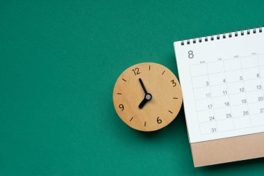 Takvim ve saati yeşil masa arka planında kapat, iş toplantısı veya seyahat planlama konsepti için planlama