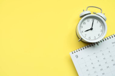 sarı masa arkaplanındaki takvim ve saati kapat, iş toplantısı ya da seyahat planlama konsepti