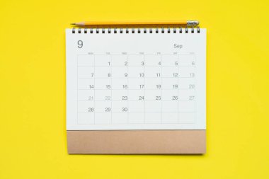 sarı masa arkaplanındaki takvim ve kalemi kapat, iş toplantısı ya da seyahat planlama konseptini planla