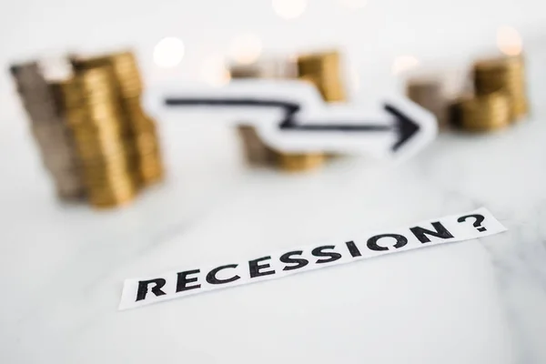 stock image recession text with arrow going down in front of decreasing stacks of coins representing negative economic growth, concept of economic issues after the pandemic