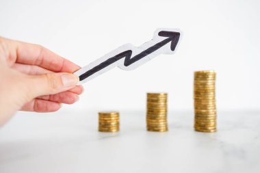 Artan para yığınları ve yukarı bakan ok, birikimlerinizi ve bileşik çıkarlarınızı artırma metaforu