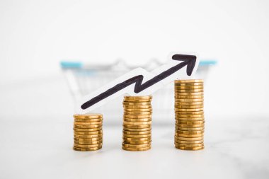 Fiyatlar yükseliyor ve artan enflasyon kavramsal imaj ile alışveriş sepeti ve artan oklu madeni para yığınları