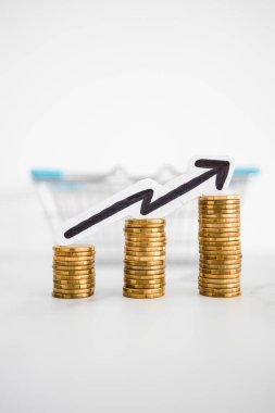 Fiyatlar yükseliyor ve artan enflasyon kavramsal imaj ile alışveriş sepeti ve artan oklu madeni para yığınları