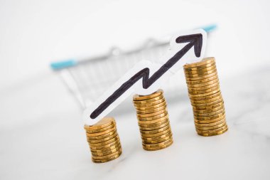 Fiyatlar yükseliyor ve artan enflasyon kavramsal imaj ile alışveriş sepeti ve artan oklu madeni para yığınları