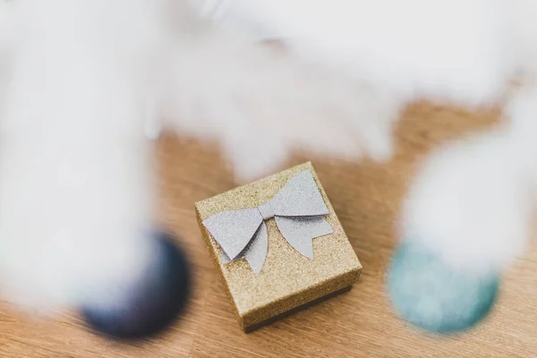 stock image golden present under christmas tree with white frosted snow style and blue and teal out of focused baubles in the foreground