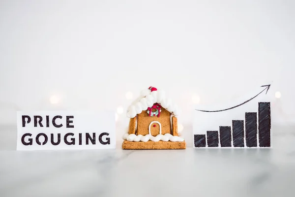 cost of living and interest rates rising around Christmas 2022, gingerbread house next to graph with Price Gouging stats going up and fairy lights in the background