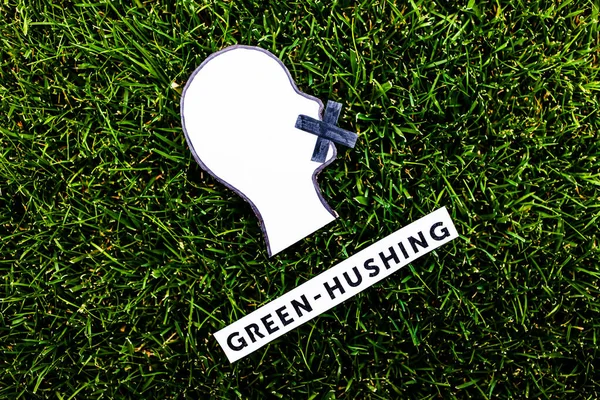 green-hushing concept about companies staying silent about their environmental footprints and policies, text and face with  mouth shut on green grass