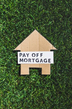 financial independence and being free from debt, Pay Off Mortgage text over cardboard house on perfect green lawn shot under strong sunshine