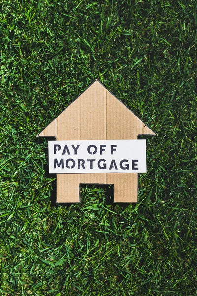 financial independence and being free from debt, Pay Off Mortgage text over cardboard house on perfect green lawn shot under strong sunshine