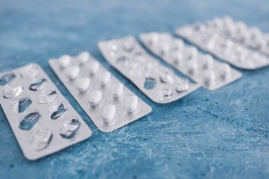 multivitamins pills or medicine tablets into blister packs next to other empty ones, concept of healthcare prescription and nutritional supplements