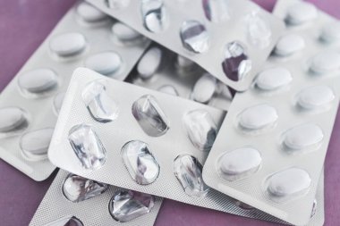 close-up of multivitamins pills or medicine tablets into blister packs next to other empty ones, concept of healthcare prescription and nutritional supplements