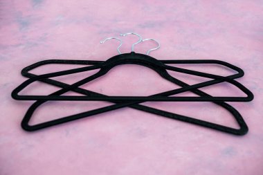 moda ve alışveriş konsepti, bir grup elbise askısı pembe arka planda geometrik şekil yaratıyor