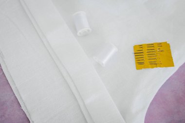 beyaz keten şortlu, iplik ve iğneli ve yarım yamalak kenarlı, sığ bir alan derinliğinde çekilmiş.