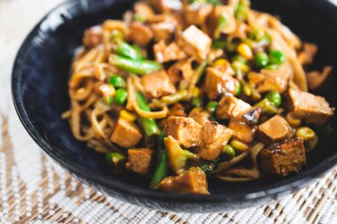 Bitkisel pirinç eriştesi, karışık yeşillikler ve marine edilmiş tofu küpleri, sağlıklı vegan yemek tarifleri.