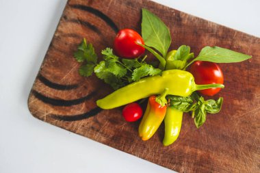Kırsal ahşap kesim tahtasında taze kırmızı biber ve bitkiler. Basit, sağlıklı malzemeler kavramı.