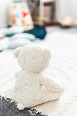 Beyaz oyuncak ayı güzel mutlu ve dağınık bebek odasında ya da renkli ahşap oyuncaklar ve yumuşak yastıklar ve halılar, çocukluk öğrenimi ve ev dekorları ile çocuk odasında görülür.